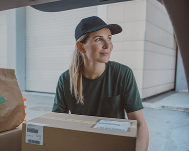 delivery woman removing package from delivery van
