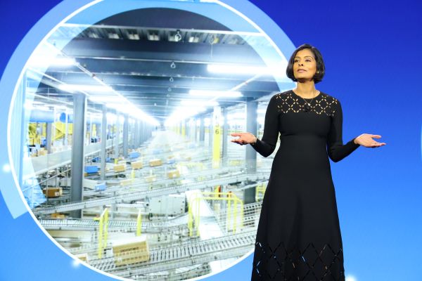 Prathibha Rajashekhar, SVP, Innovation & Automation, Walmart US, shares the news of Walmart's drone delivery expansion in front of a screen showing the inside of a distribution center.