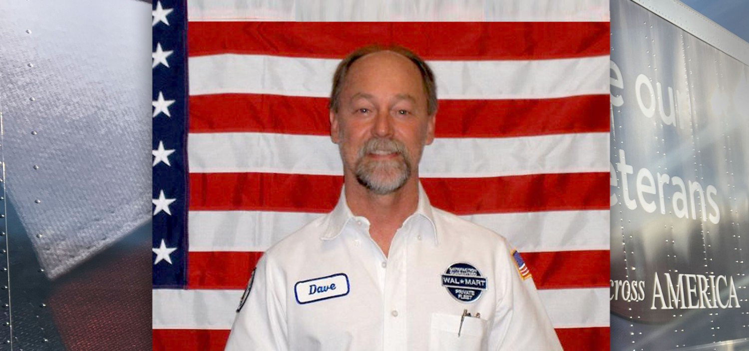 Driver Dave smiling at the camera standing in front of an American flag