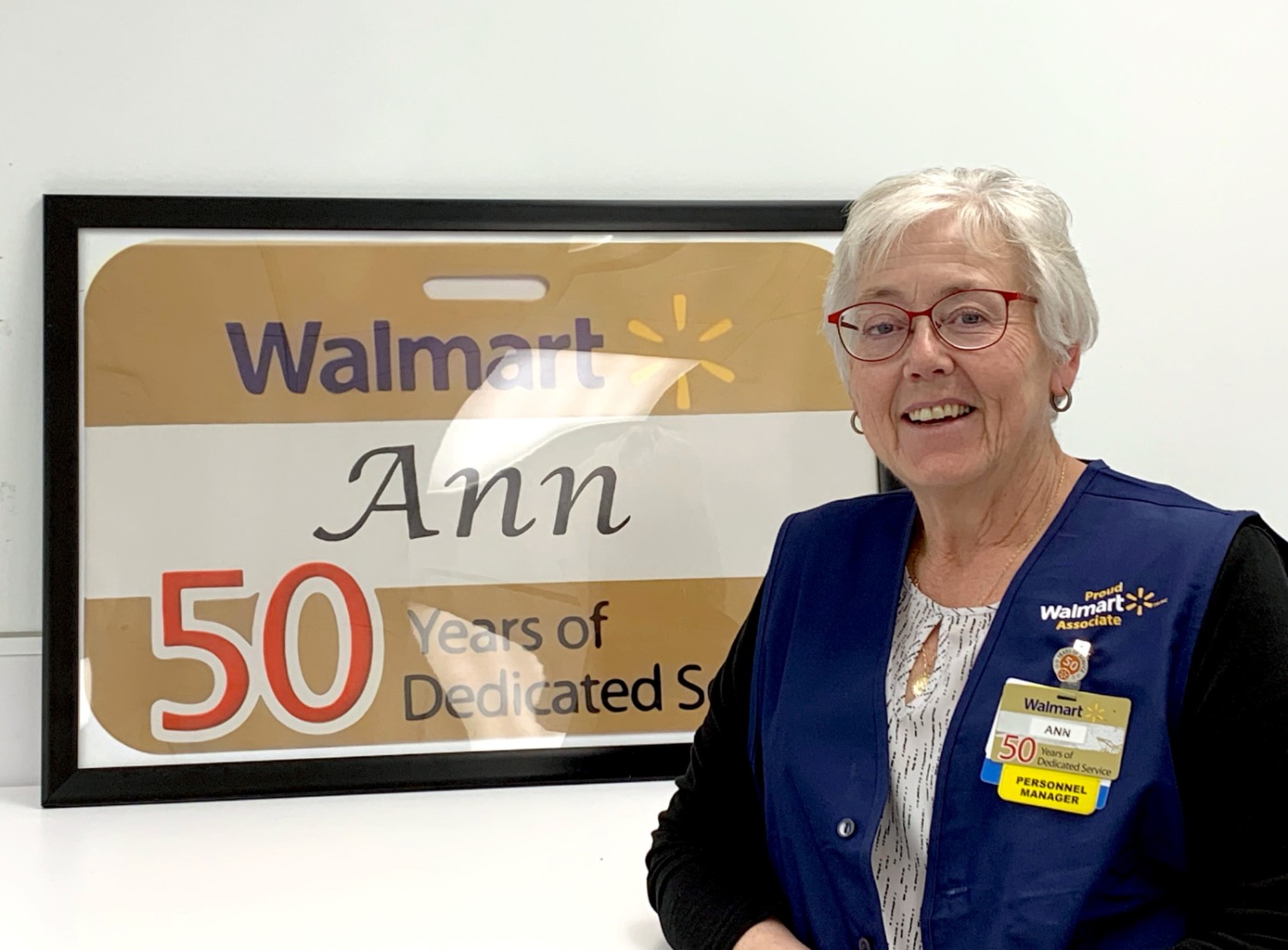Ann standing in front a 50 years of service framed badge