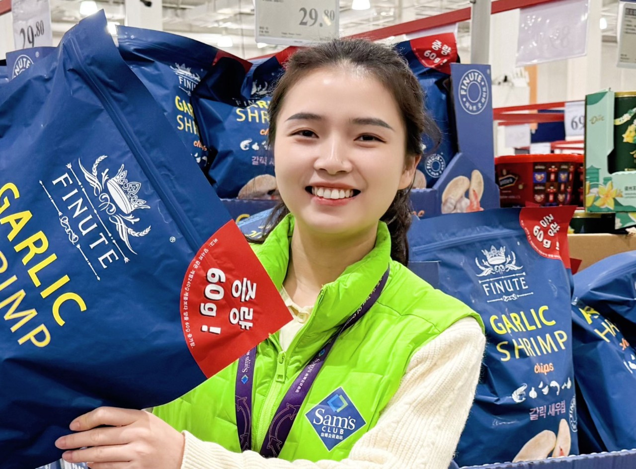 Sam’s Club associate Li Jialing smiles and holds large bag of chips.